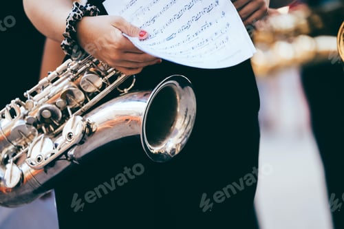 Preview: Musician holding saxophone and sheet music, preparing for a street concert in spain