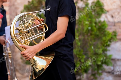 Preview: Young musician holding a french horn, preparing for a street performance in spain