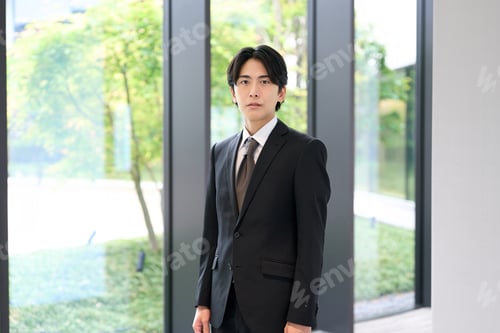 Preview: An Asian businessman standing with a serious expression.