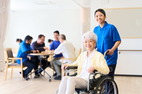 Preview: Senior citizen in a wheelchair and foreign caregiver at a nursing home