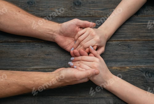 Preview: Loving man woman couple holding hands on dark wooden background. Gentle care support concept represe