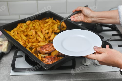 Preview: Woman holds empty white plate over baking tray with roasted potatoes.