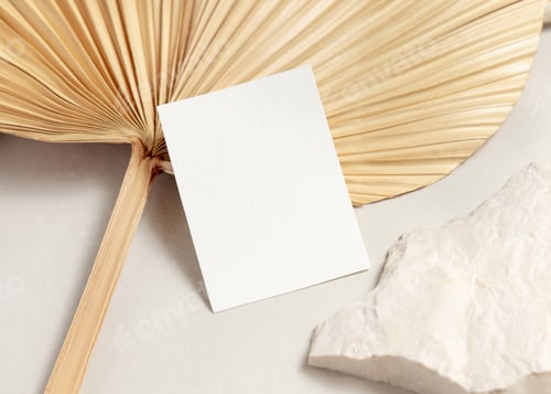 Preview: Blank card mockup with dried palm leaf on beige stone top view, boho wedding stationery