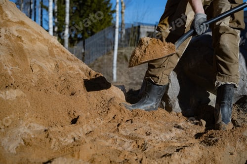 Preview: Unrecognizable man fills a drainage trench with sand on his countryside property, working outdoors w