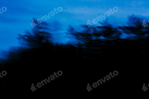 Preview: View from a car of roadside trees, blurred motion, at dusk.