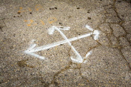 Preview: Multl-direction chalk arrows on pavement, cracks in the surface, potholes and concrete for repair.