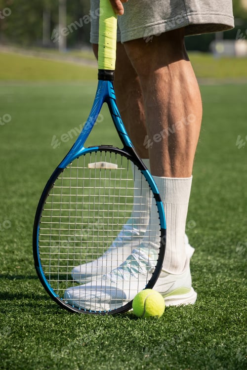 Preview: Tennis racket and ball near athlete legs on sports court