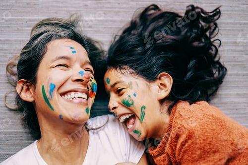 Preview: Happy latin mother and daughter having fun with painted face at home - Family love life concept