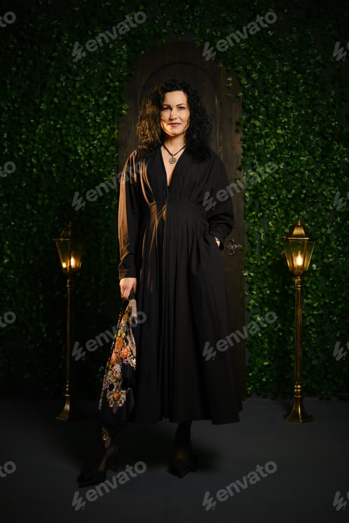 Preview: Woman stands in a dimly lit area with decorative plants and vintage lamps while holding a bag