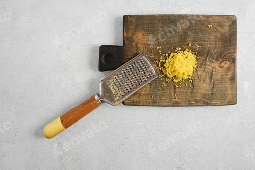 Preview: Pile of shredded lemon zest and kitchen grater on cutting board