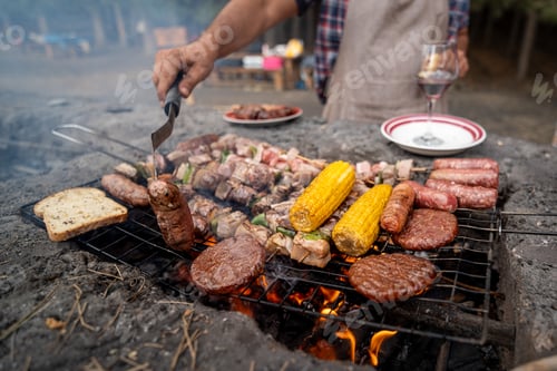 Preview: Hands flip sizzling meats over glowing coals. Hands flip sizzling meats over glowing coals