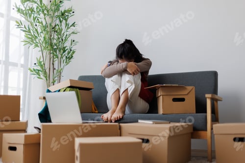 Preview: Stressed woman sitting surrounded by cardboard boxes feeling overwhelmed