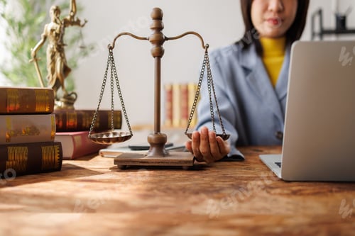 Preview: Lawyer balancing scales of justice working on laptop