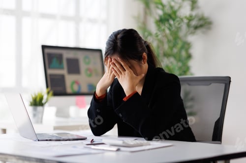 Preview: Stressed businesswoman covers her face, suffering from burnout and a headache while working at her o