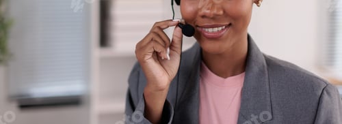 Preview: Smiling customer service professional wearing a headset, adjusting the microphone while offering sup