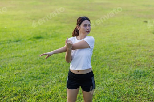 Preview: Young woman stretching arm outdoors preparing for exercise