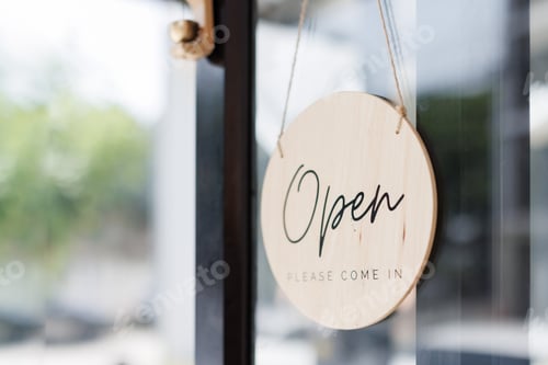 Preview: Wooden open sign hanging on glass door inviting customers