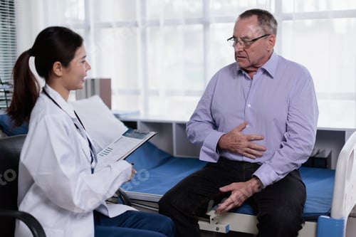 Preview: Young female doctor having a medical consultation with a senior male patient experiencing abdominal