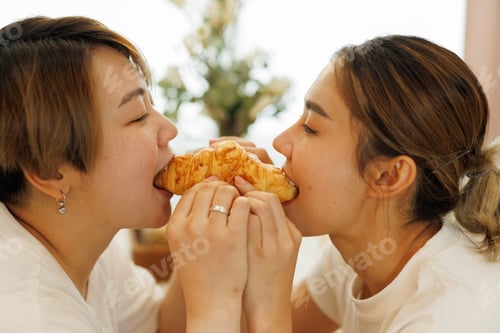 Preview: Romantic lesbian couple sharing a croissant, enjoying a sweet breakfast moment together, symbolizing