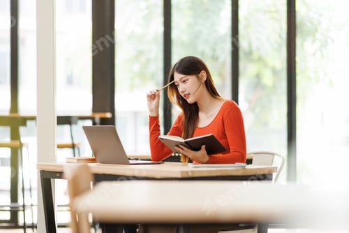 Preview: Asian college student learning online with laptop and notebook