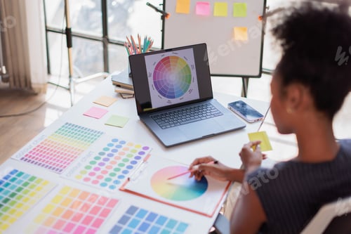 Preview: Creative graphic designer making color selections for a new project, working on a laptop displaying
