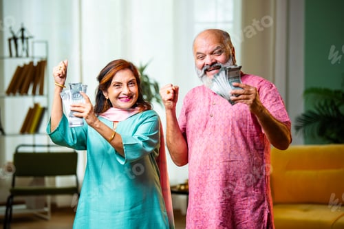 Preview: Excited Indian Retired Couple Celebrating Wealth with Five Hundred Rupee Notes