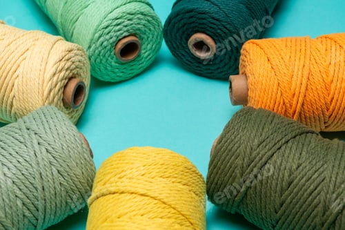 Preview: Circular Arrangement of Mint, Yellow, Green, and Teal Macrame Cords on a Turquoise Background