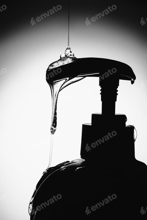 Preview: Liquid shower gel or shampoo dripping from pump bottle dispenser in monochrome