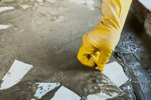 Preview: Gloved hand laying broken ceramic tiles into cement mortar. Upcycling old materials. DIY mosaic floo