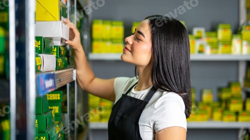 Preview: Female retail employee arranging new products and inventory in a store storage room