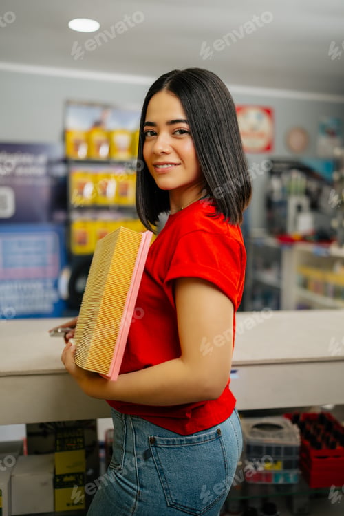 Preview: Woman standing in an auto parts store holding a car air filter, smiling at the camera