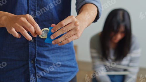 Preview: Criminal Opens A Condom In The Foreground While A Scared Young Female Victim Sits Bound
