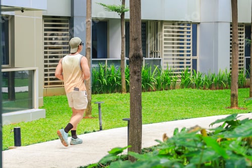 Preview: Young Man Jogging Along A Paved Path In A Courtyard Garden Surrounded By The Modern Facade