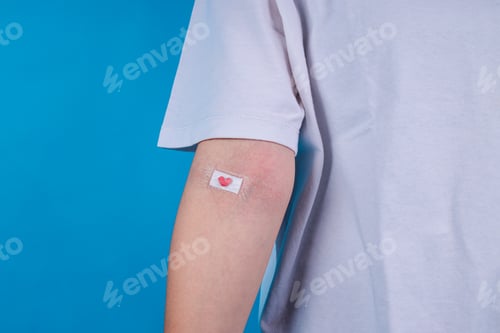 Preview: Volunteer Shows Medical Bandage With Small Heart On Their Arm After Blood Donation