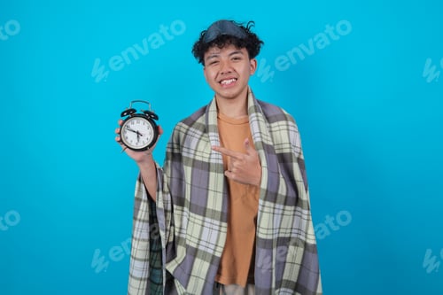 Preview: Happy Young Asian Man Smiling And Pointing At An Alarm Clock