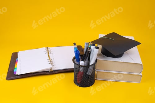 Preview: Graduation Cap And Planner On Yellow Background