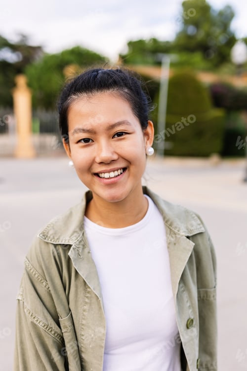 Preview: Happy young asian teen girl smiling at camera standing at city street