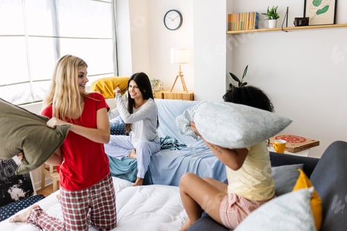 Preview: Young women having pillow fight at slumber party