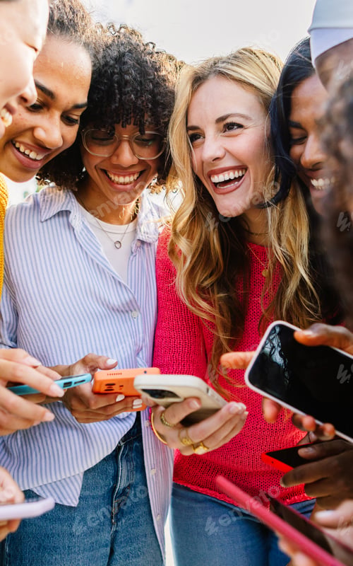 Preview: Happy female group using mobile phone together outdoors.