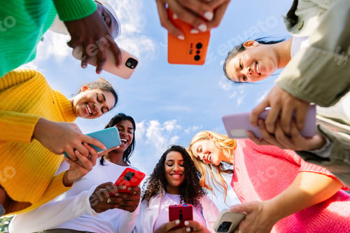 Preview: Low angle view of young group of multicultural women using mobile phones