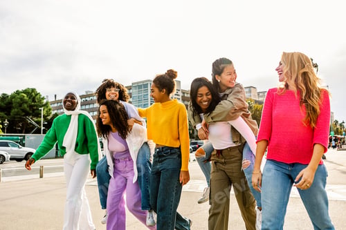 Preview: Young friends walking and laughing together on a sunny street
