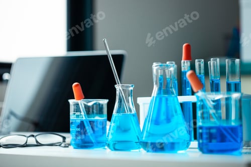 Preview: A table with a laptop, a few beakers and test tubes, and a blue liquid. The table is set up for a sc