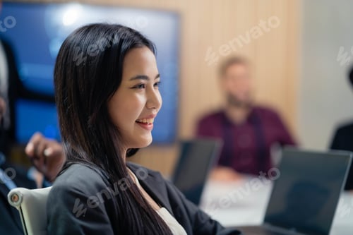 Preview: A woman is sitting at a table with a laptop and a monitor. She is smiling and she is happy