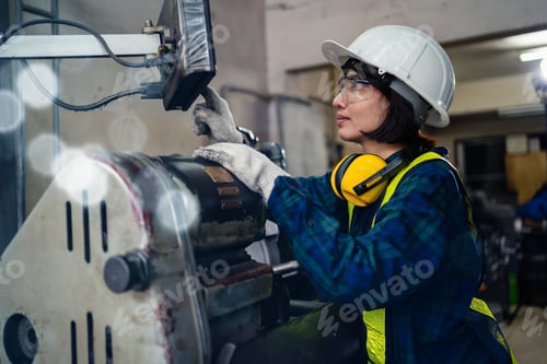 Preview: A female mechanical engineer or mechanic in a safety uniform checks the readiness of a lathe inside