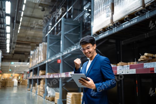 Preview: concept of success. An Asian businessman in a large warehouse checks cardboard boxes in a logistics