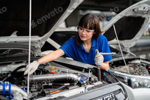 Preview: A female mechanic checking vehicle safety in a car service center. Woman mechanic fixing engine. Con