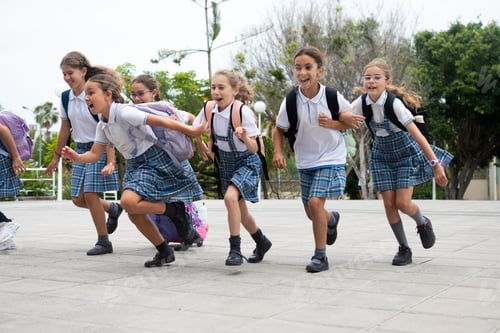 Preview: Excited elementary school girls running together in the school courtyard before class
