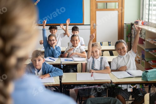 Preview: Elementary school students raising their hands to answer a question in classroom