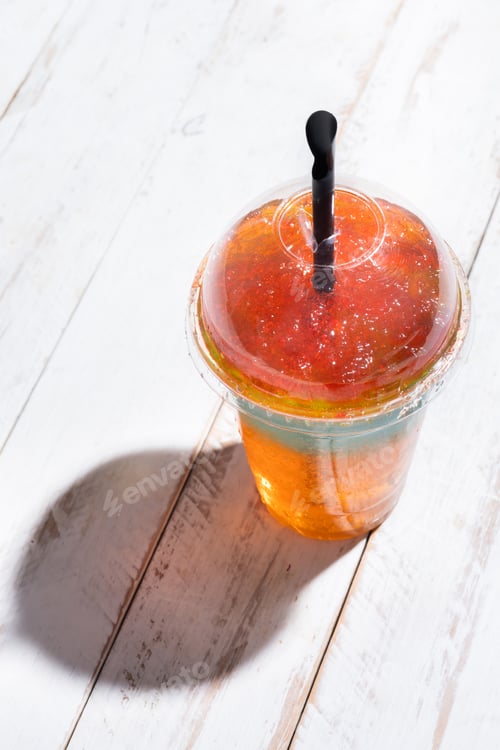 Preview: Colorful Frozen Slushie Drink in Plastic Cup on White Wooden Table