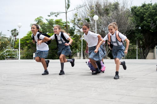 Preview: Excited elementary school girls running together in the school courtyard before class